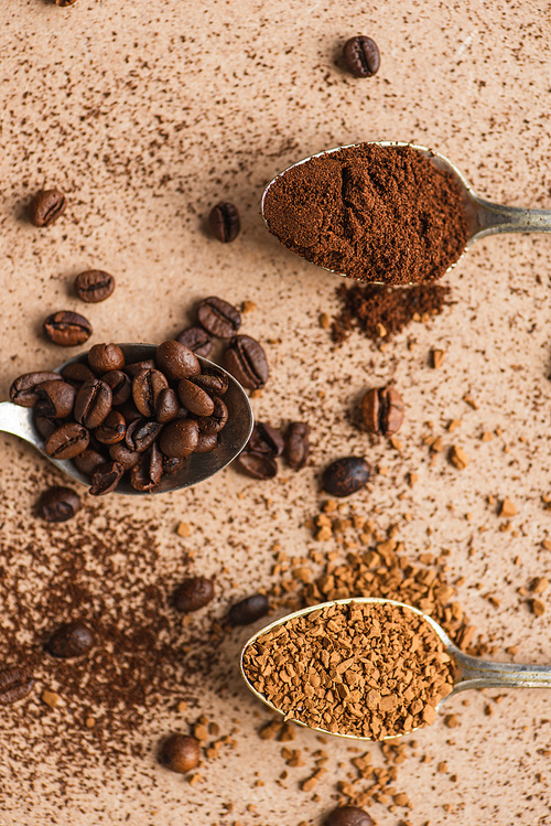 top view of ground, instant coffee and beans in spoons on beige surface