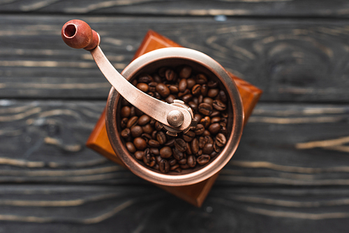 selective focus of vintage coffee grinder with coffee beans on wooden surface