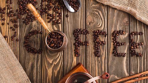 top view of coffee lettering made of beans and cezve on wooden surface