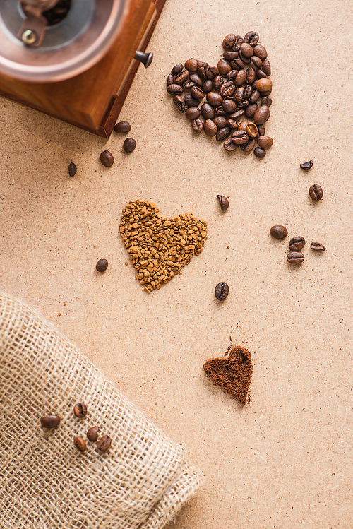 top view of vintage coffee grinder near hearts and burlap on beige surface