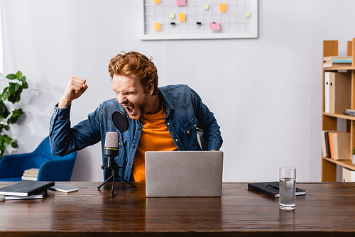 angry redhead announcer screaming in microphone and showing clenched fist