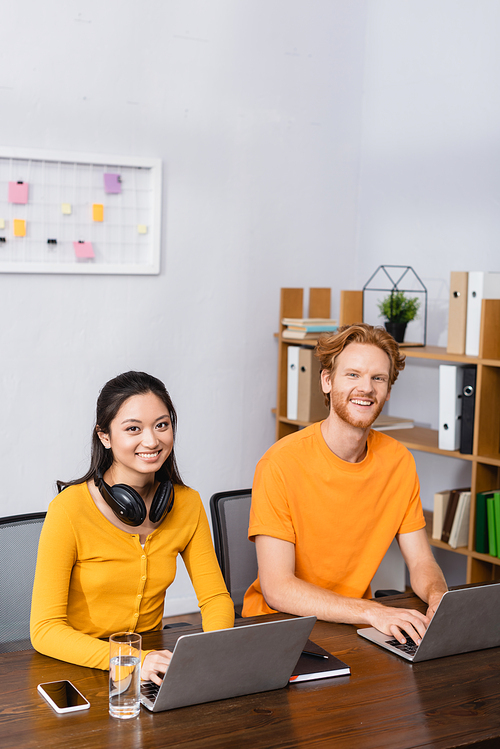 excited multicultural freelancers  while working on laptops at home