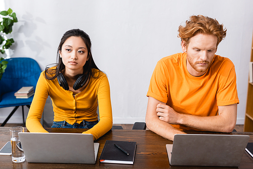 interracial couple of thoughtful freelancers using laptops at home