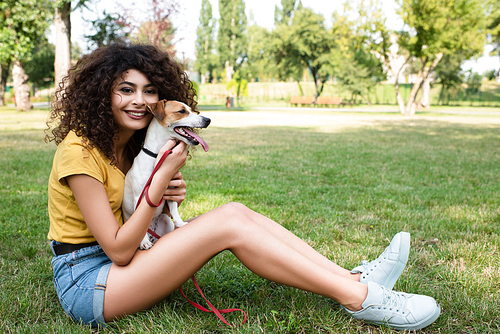 Selective focus of young woman sitting on grass with dog and 