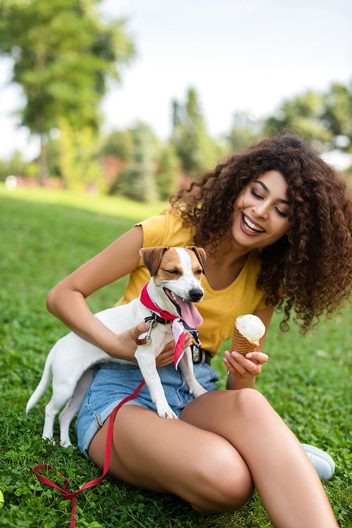 Selective focus of young woman sitting with ice cream and looking at dog