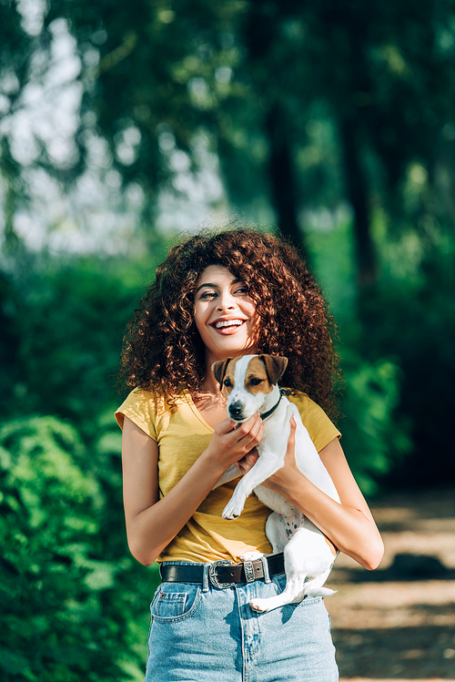laughing woman  while holding jack russell terrier dog in park