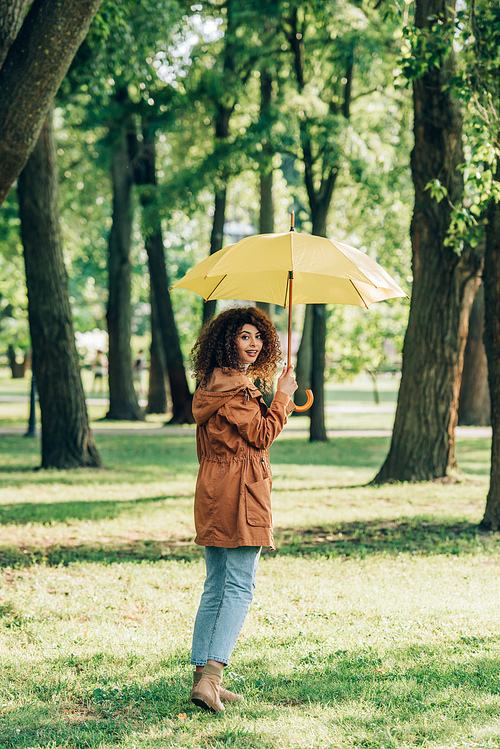 Selective focus of woman with umbrella  on meadow in park