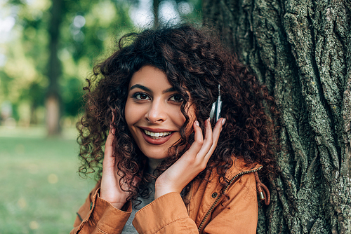 Young woman touching headphones and  in park