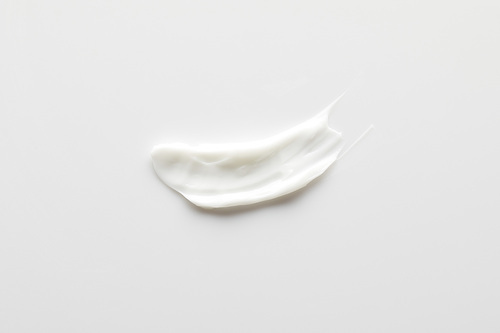 Top view of cosmetic cream brushstroke on grey background