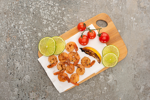 top view of fried shrimps with cherry tomatoes and lime on grey concrete background