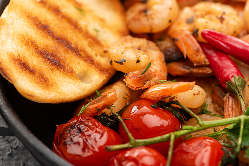 close up view of fried shrimps with grilled bread, tomatoes, chili peppers