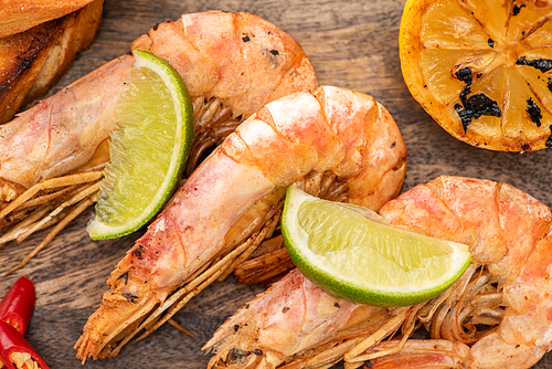 close up view of fried shrimps with lemon, chili and lime on wooden board
