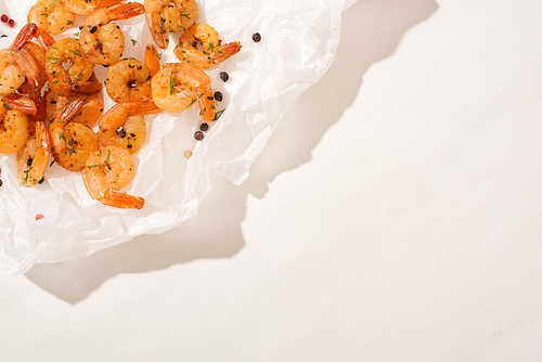 top view of fried shrimps on parchment paper with pepper on white background