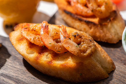 close up view of canape with toast bread and fried shrimps on wooden board