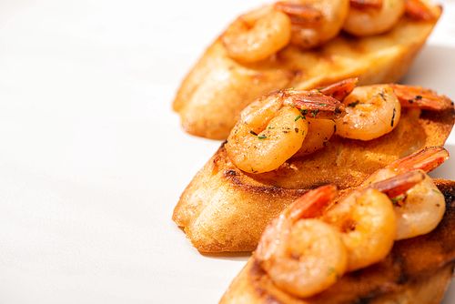 close up view of canape with toast bread and fried shrimps on white background