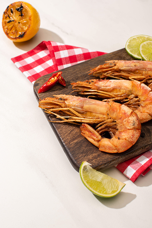 fried shrimps on wooden board on plaid napkin with sauce and lime on white background