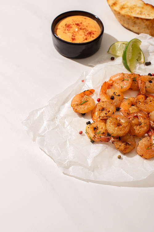 fried shrimps on parchment paper with sauce and lime on white background