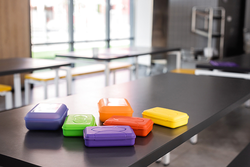 colorful plastic lunch boxes on table in school canteen