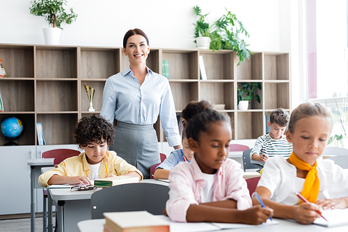 Selective focus of teacher  near multiethnic pupils during lesson in school