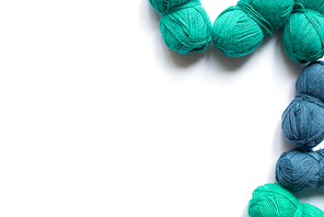 top view of blue and green wool yarn on white background with copy space