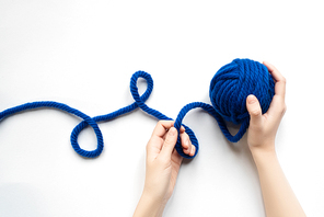 cropped view of woman holding of blue wool yarn and knitting needles on white background