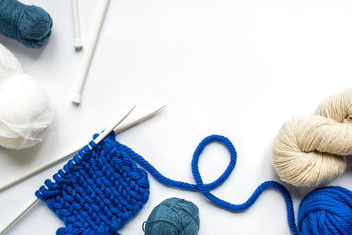 top view of wool yarn and knitting needles on white background
