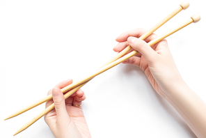 top view of female hands with knitting needles on white background