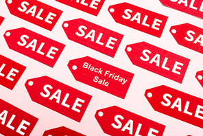 top view of red labels with sale and black friday lettering on pink