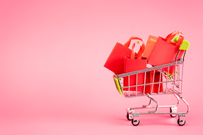 shopping bags in small trolley on pink, black friday concept