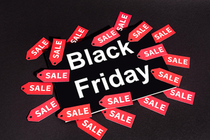 placard with black friday lettering near sale tags on dark background
