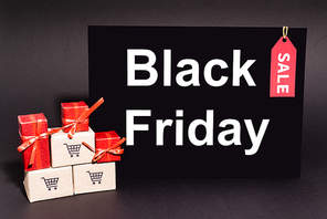 gifts near small carton boxes near placard with black friday lettering on dark background