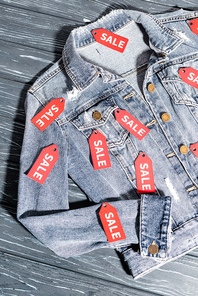top view of red sale tags on blue denim jacket, black friday concept