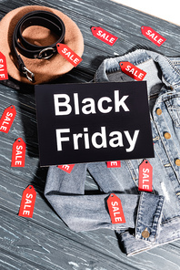 top view of placard with black friday lettering on blue denim jacket near beret and belt