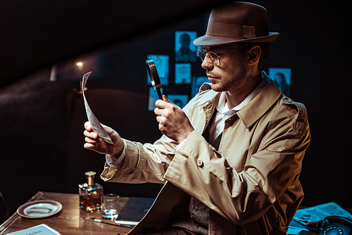 Detective in trench coat looking at photo through magnifier