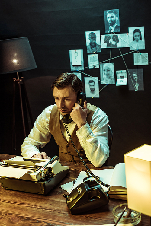 Detective sitting at table with typewriter and talking on telephone in office