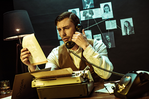 Detective reading document while talking on telephone in office