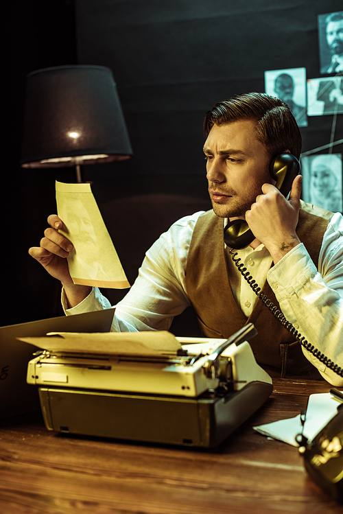 Detective reading document while talking on telephone in office