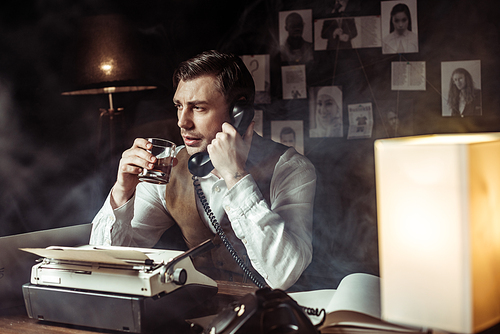 Detective talking on telephone and drinking cognac in office