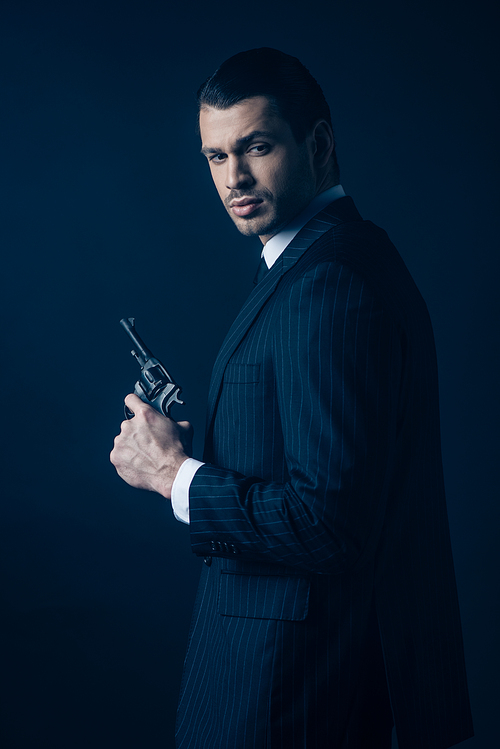 Side view of gangster with gun on dark background