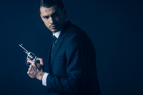 Side view of gangster with revolver on dark background