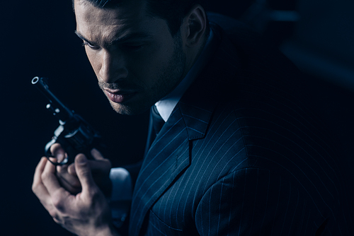 Gangster with revolver in clenched hands on dark background