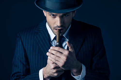 Mafioso lighting cigar and  on dark background