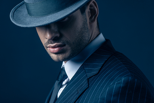 Portrait of mafioso in felt hat on dark blue background