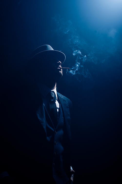 Silhouette of mafioso smoking cigarette on dark blue background