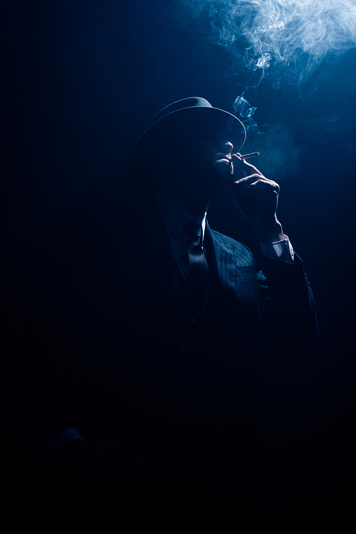 Silhouette of mafioso smoking cigarette on dark background