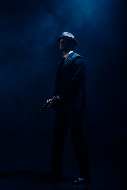 Dangerous gangster with weapon in clenched hands on dark blue background