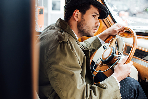 Selective focus of concentrated mafioso holding steering wheel driving car