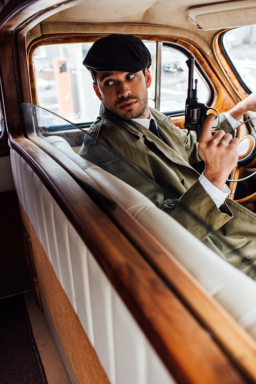 Selective focus of gangster with gun looking back in car