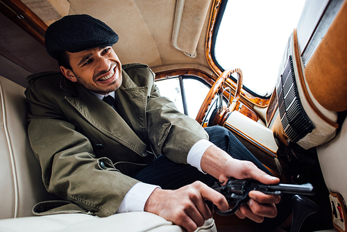 Low angle view of tense mafioso with gun in ambush sitting in car