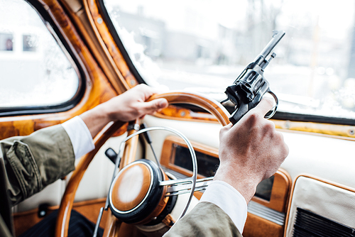 Cropped view of mafioso holding gun and driving car